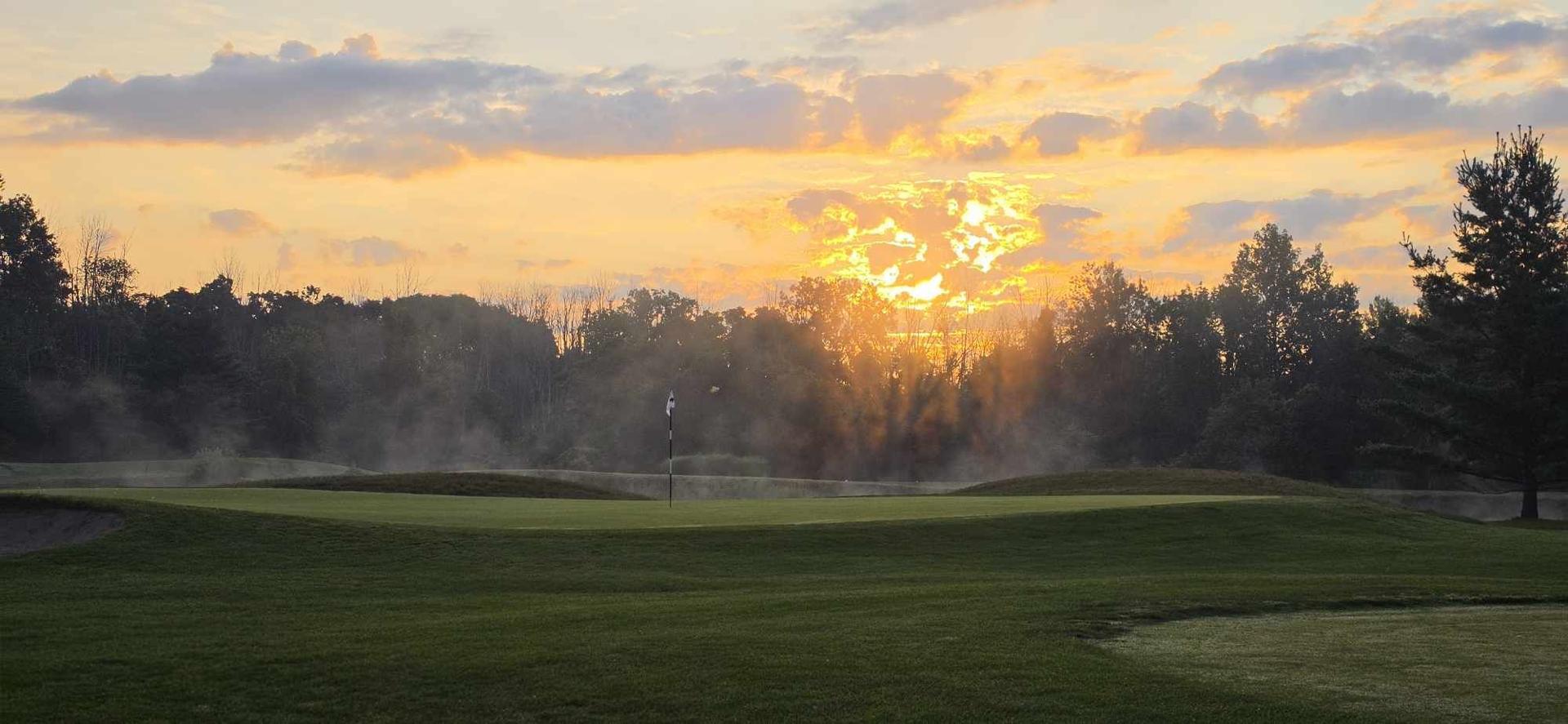 Sunset over a green with bunkers on an Upstate New York golf course